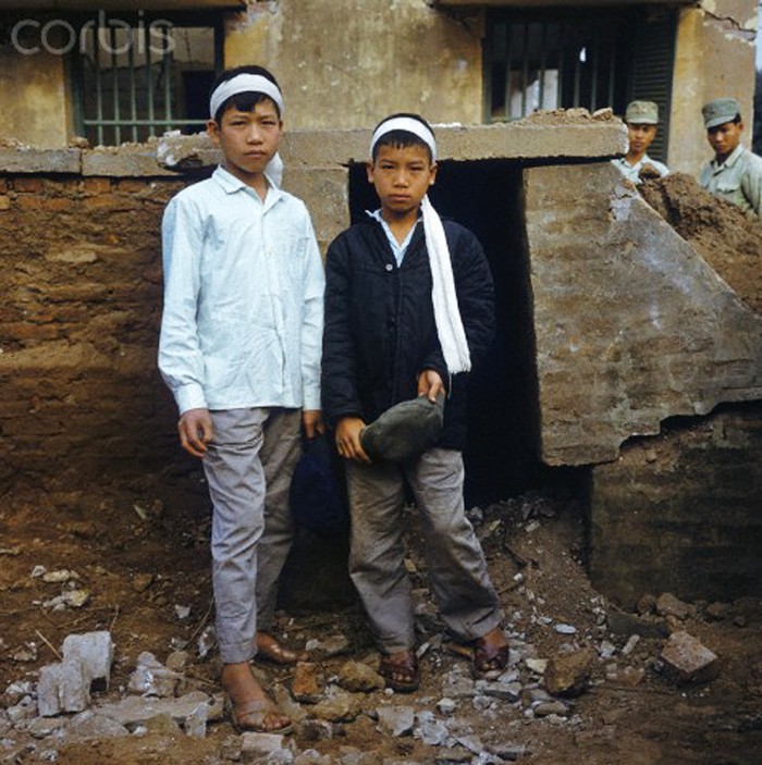 Hai đứa trẻ trước ngôi nhà đã bị phá hủy sau trận bom của quân Mỹ tại khu phố Khâm Thiên tháng 12/1973. Người thân trong gia đình của hai em cũng đã qua đời sau trận càn. Ảnh. © Werner Schulze-dpa-Corbis.